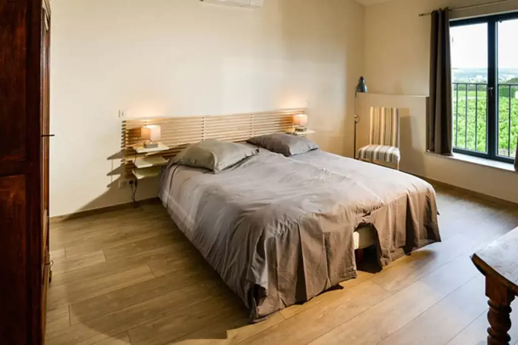 [A cozy bedroom with a big bed and a window looking out over grapevines outside.} vineyard stays near Avignon France, Domaine la Romance, hotels in vineyards france