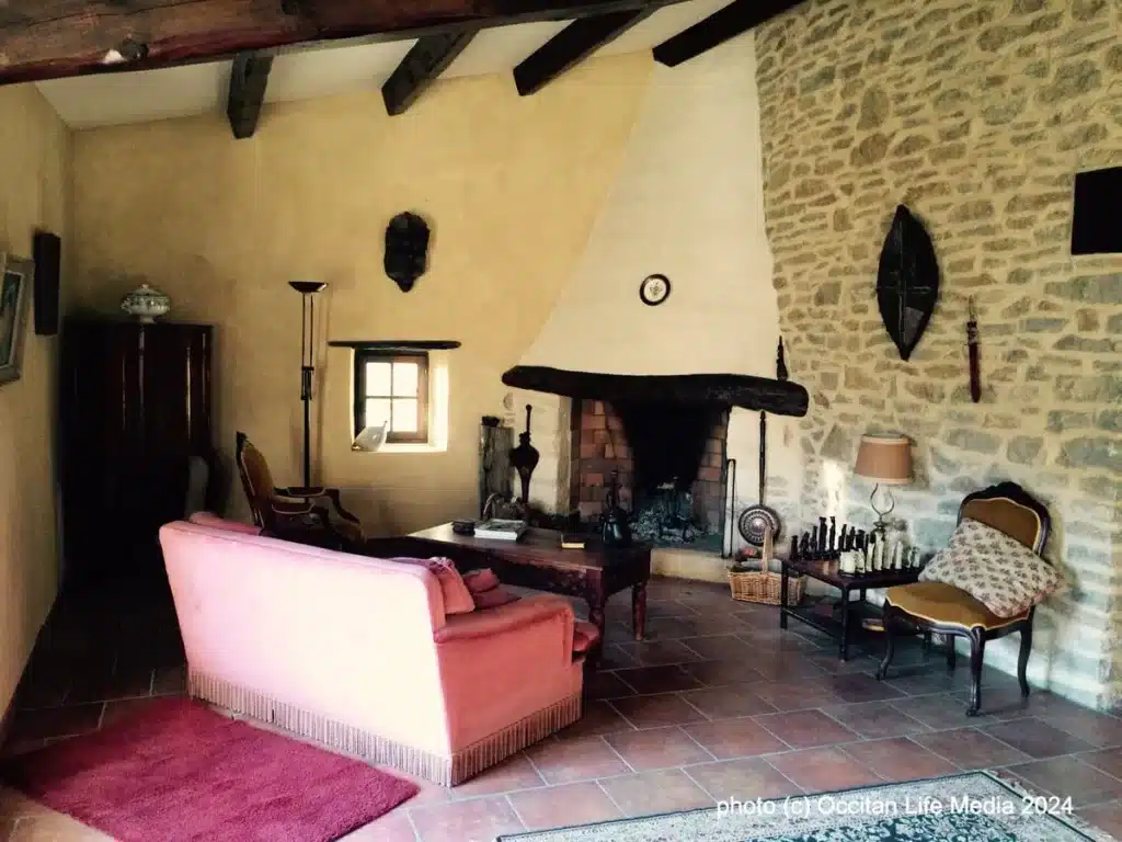 [A cozy living room with a stone fireplace and a pink couch, creating a warm and inviting atmosphere in a vacation rental south of france gard department booking airbnb]