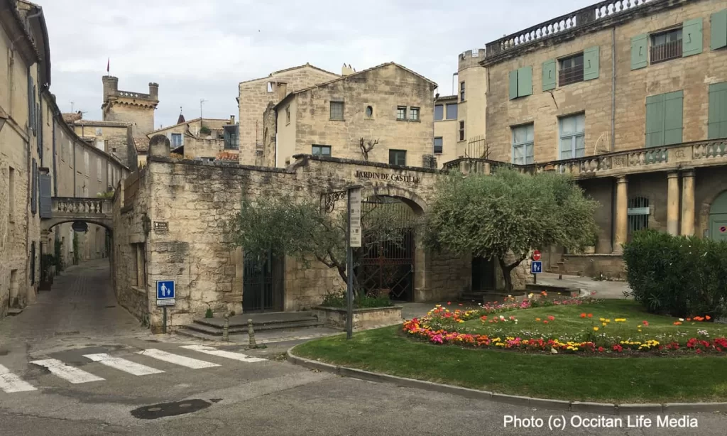 [a welcoming view of a limestone porte or gate and the ancient buildings of Uzes, a hidden gem of France]