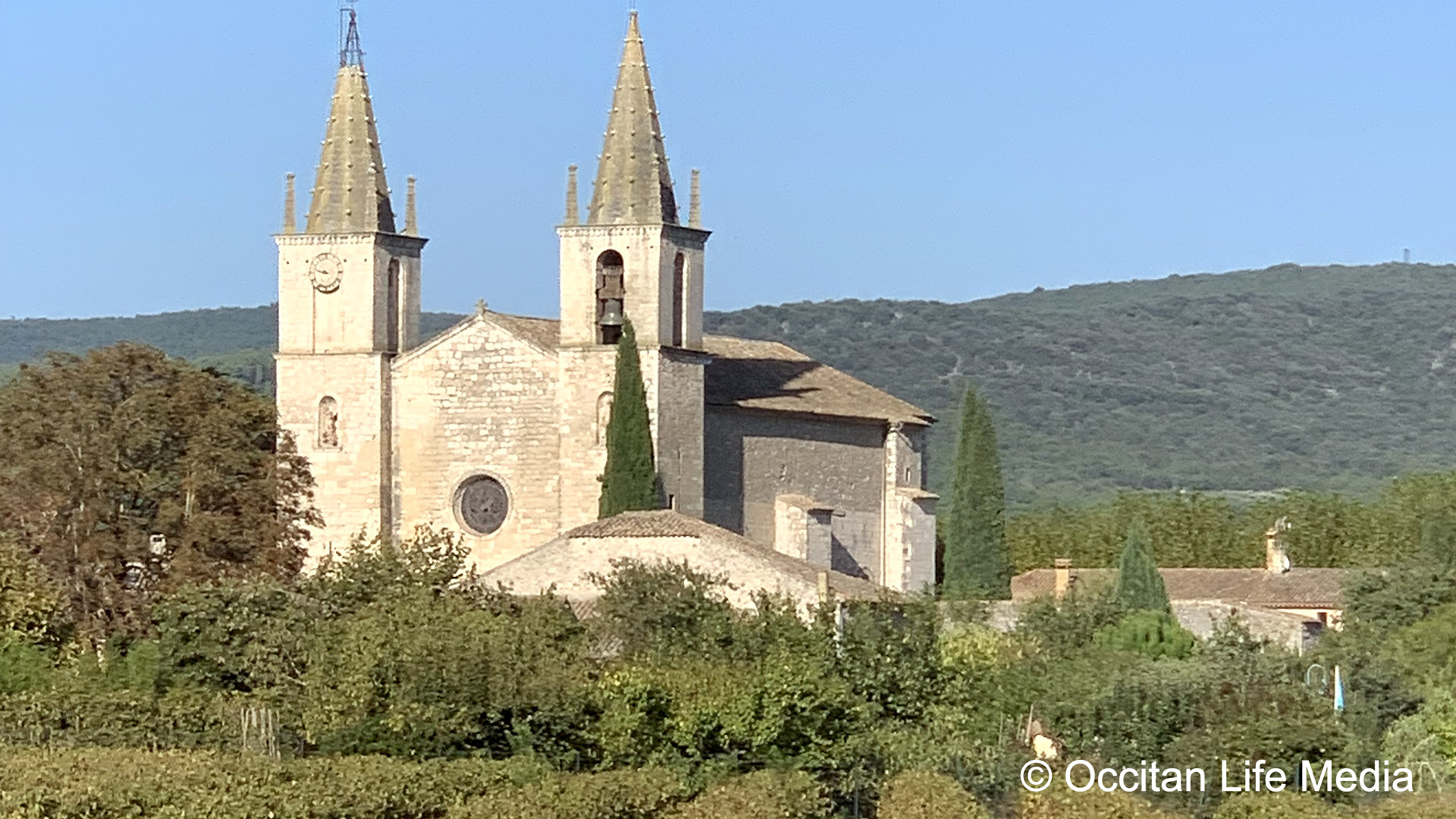 Scenic view of a hilltop church with twin spires, set against a backdrop of nature.